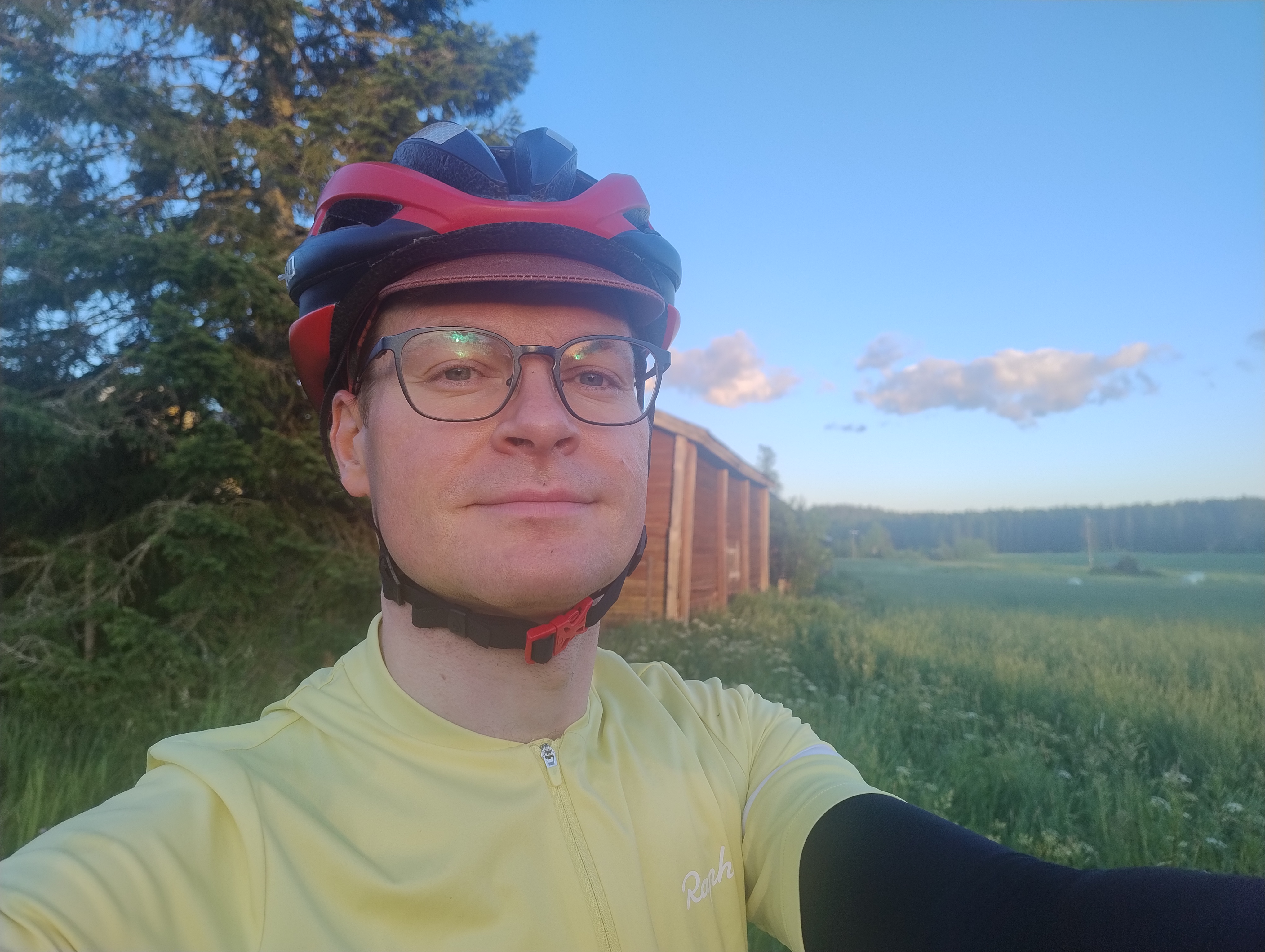 Olli maatalousrakennuksen edustalla ilta-auringossa, taustalla peltoa ja sinistä taivasta.