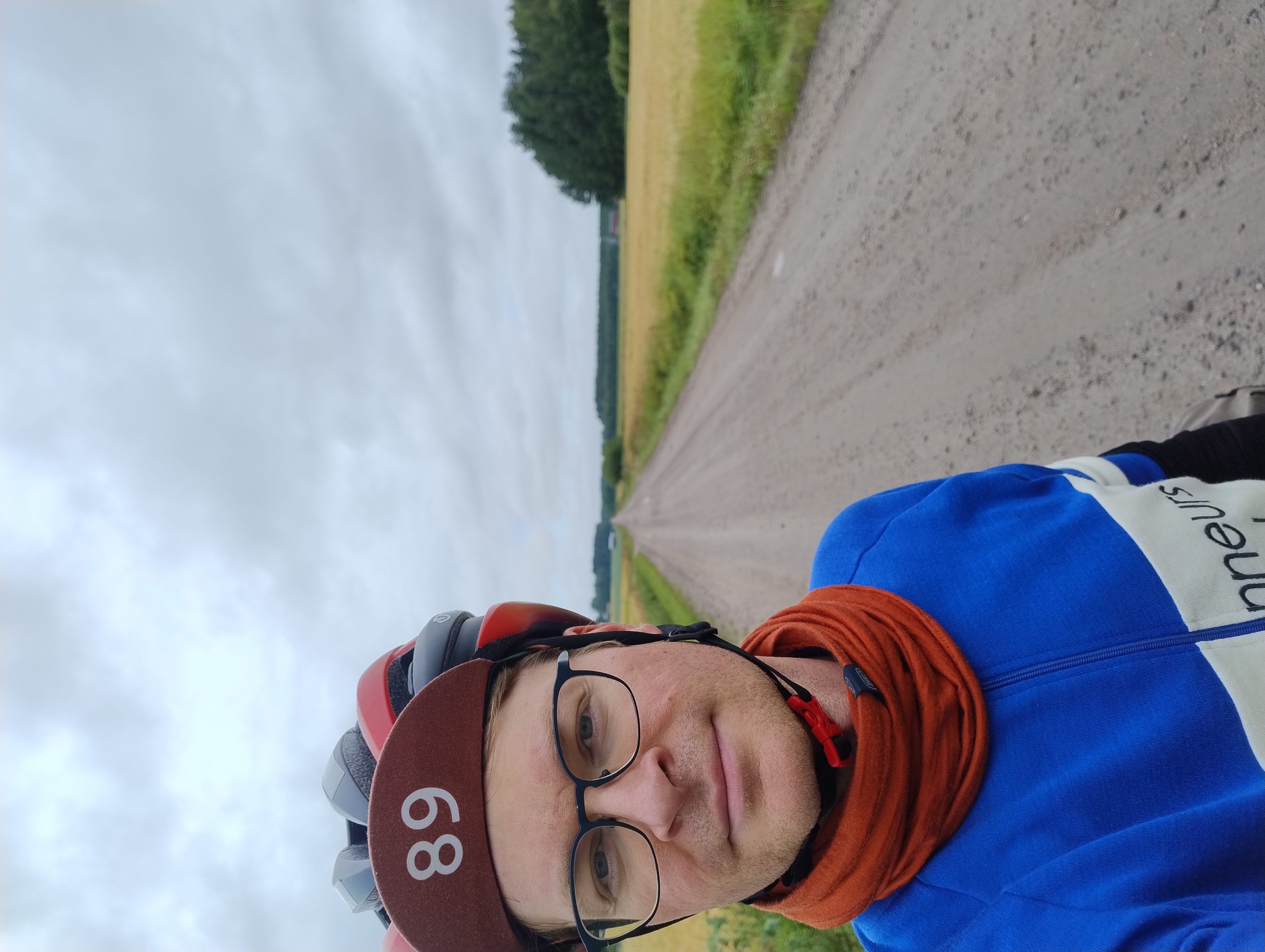 Olli seisoo peltomaisemassa, kaukaisuuteen johtaa suora hiekkatie.