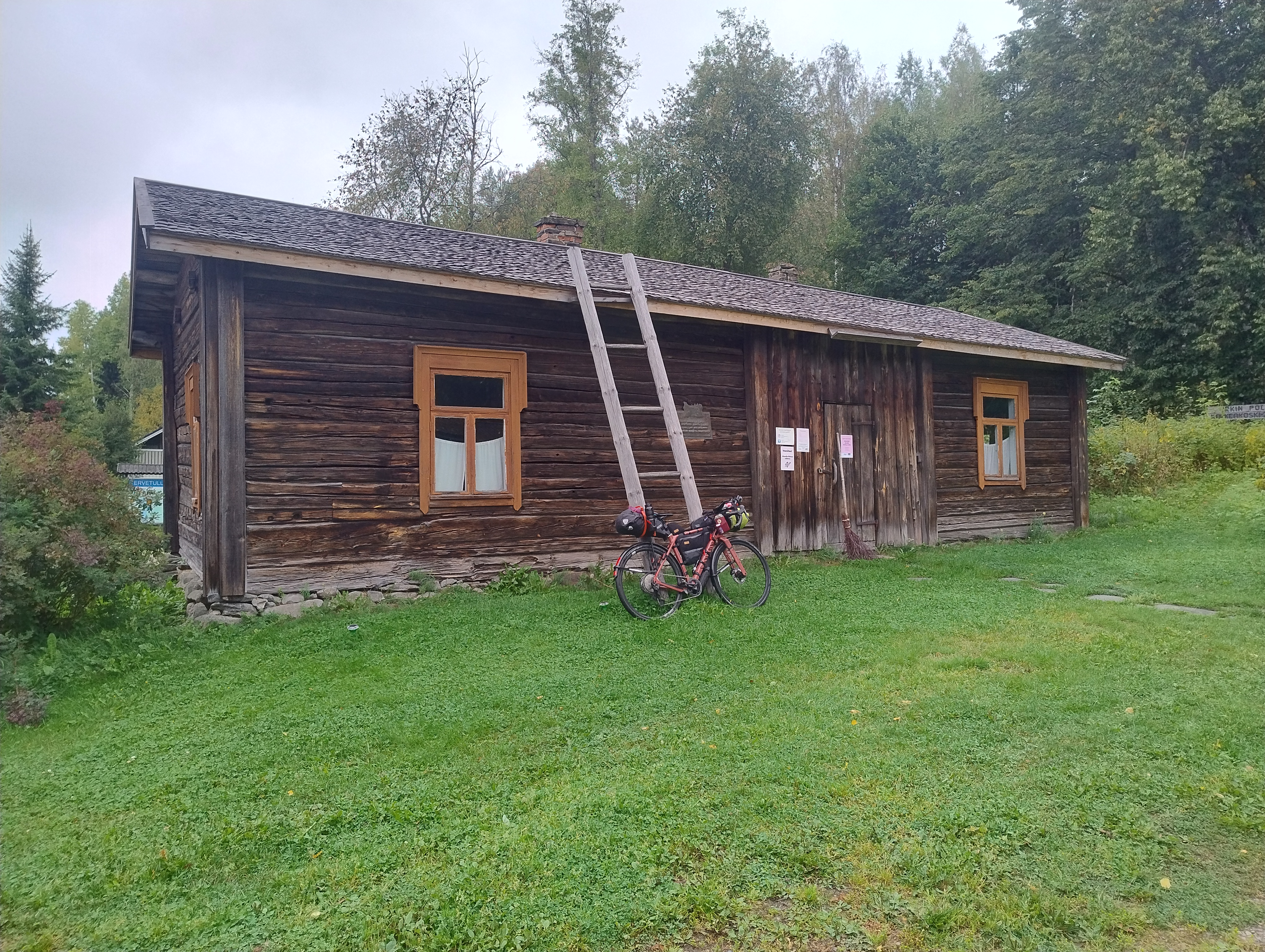Polkupyörä nojaa ruskean hirsirakennuksen seinustaan
