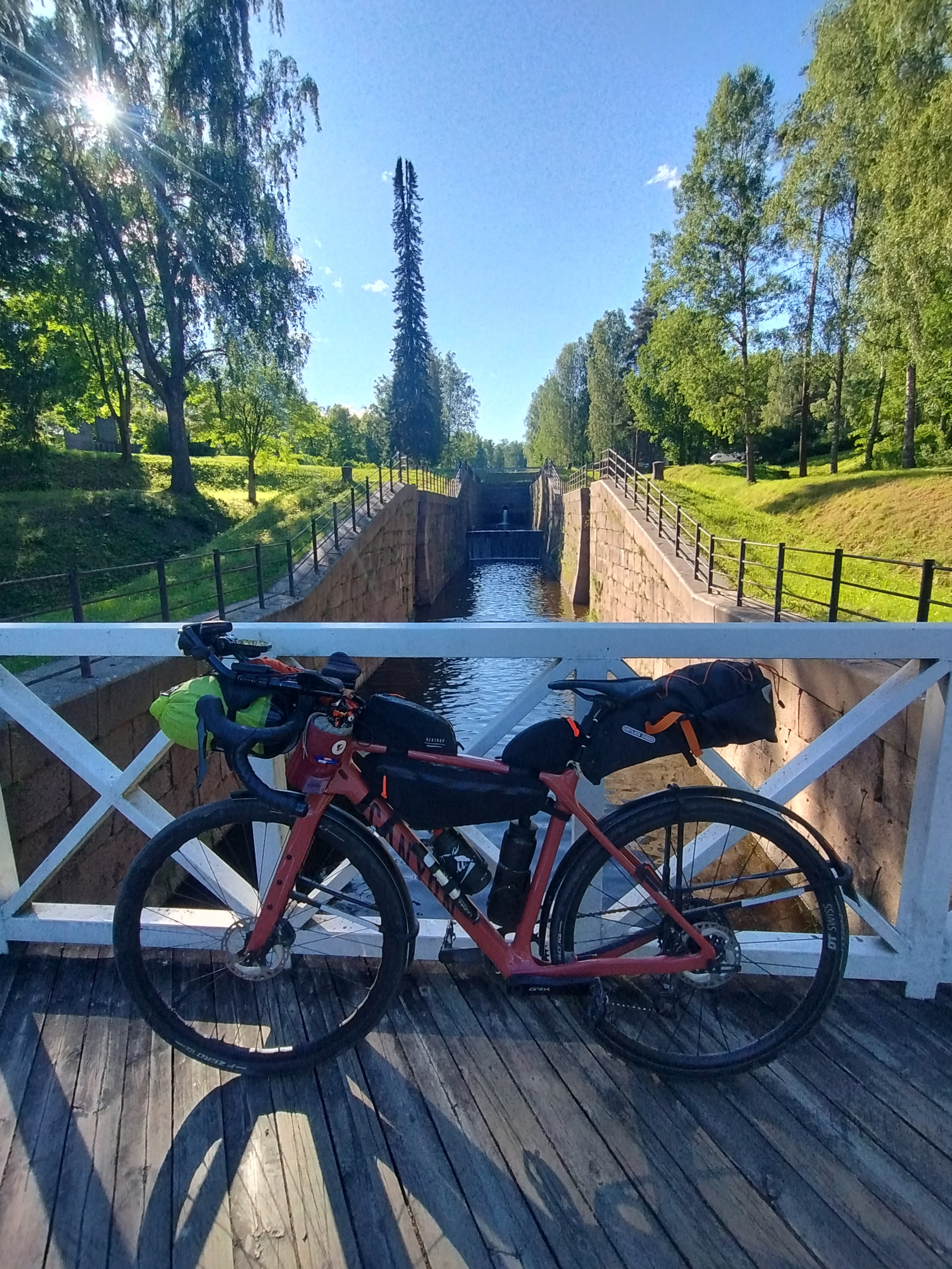 Polkupyörä nojaa kaiteeseen Saimaan kanavan museolla. Taustalla pieni kanava ja puistomaista aluetta.