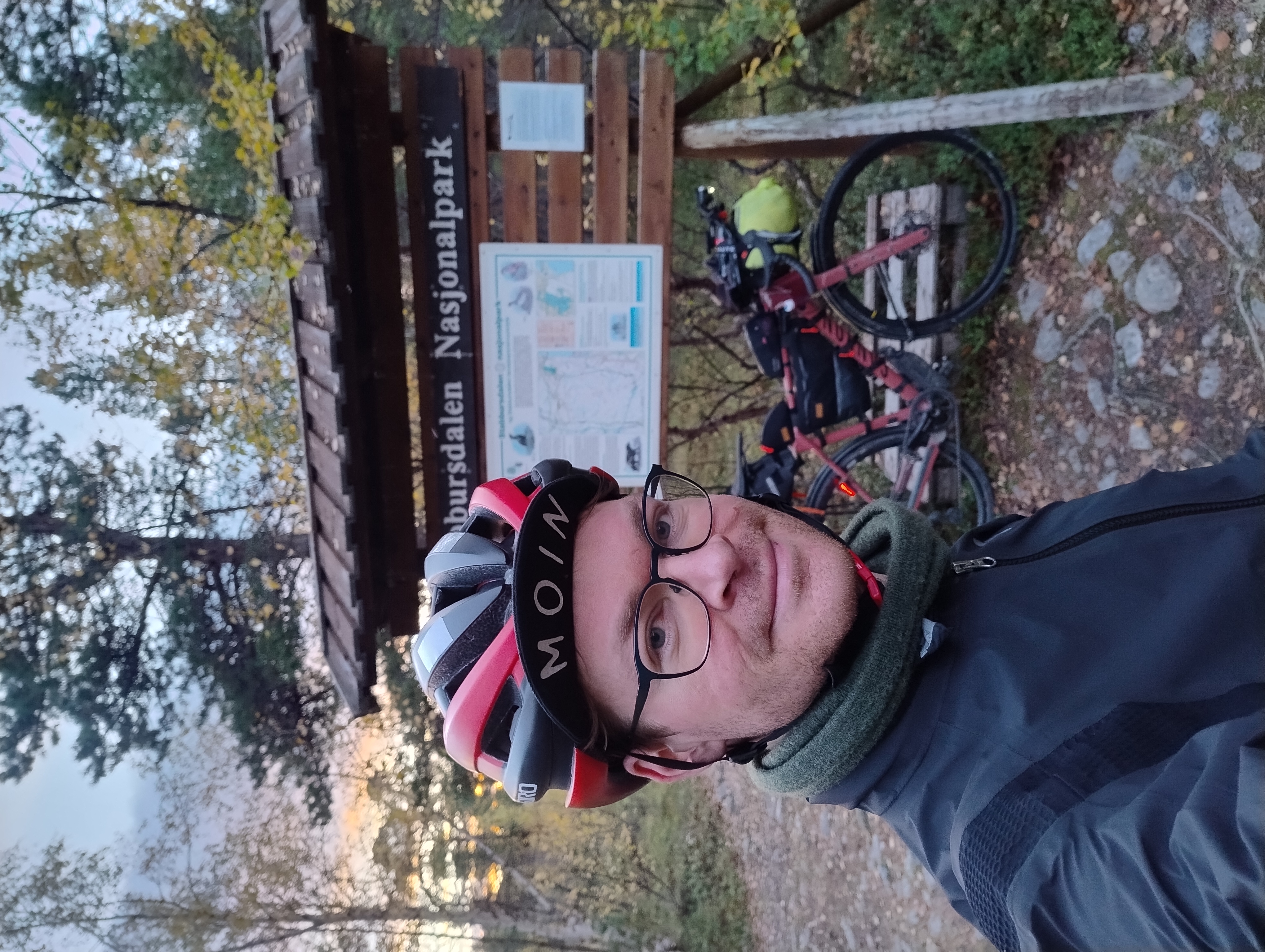 Olli kyltin edessä. Kyltissä lukee Stabbursdalen nasjonalpark. Polkupyörä nojaa kylttiin.