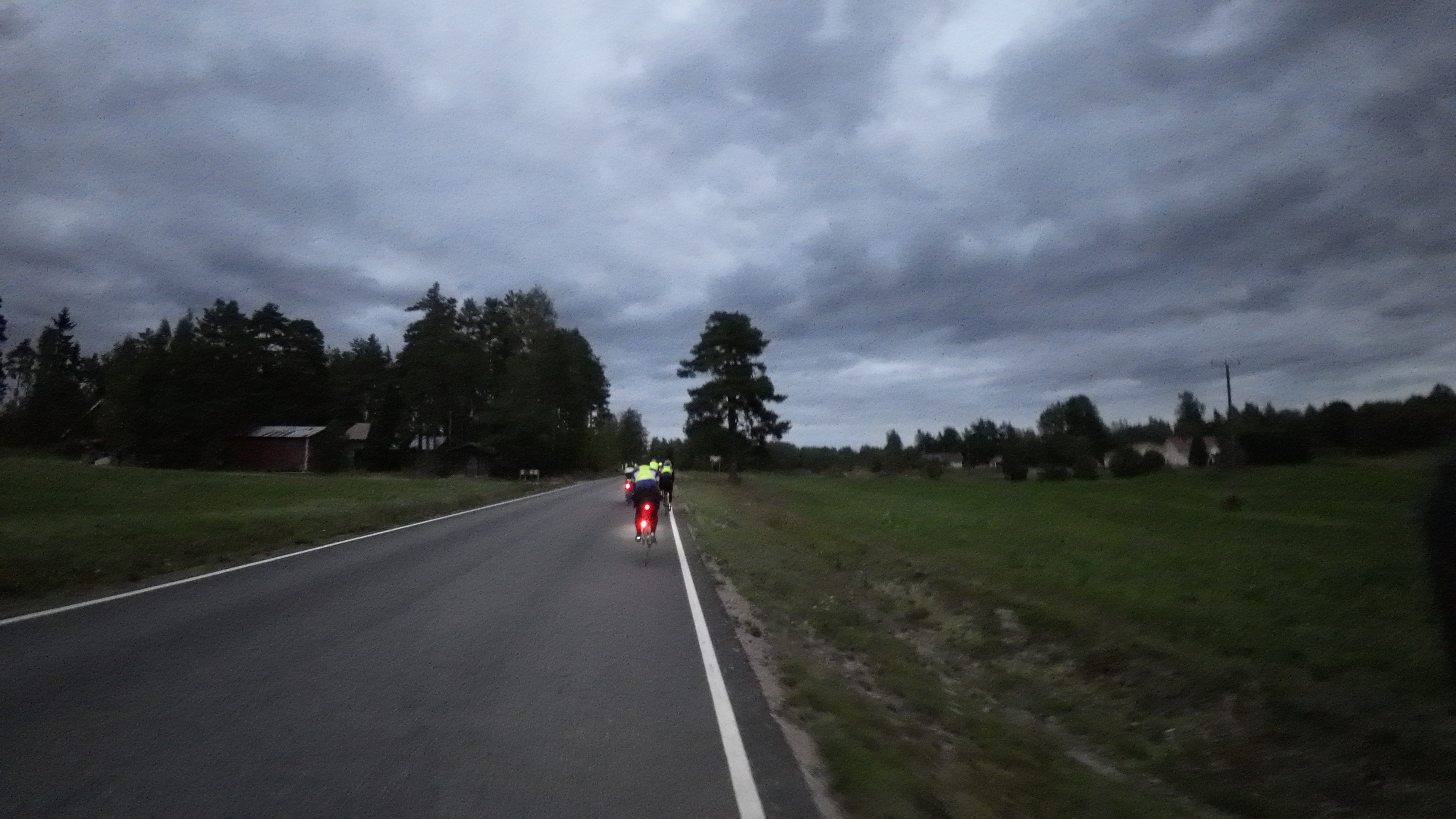 Polkupyörien punaisia takavaloja tummuvalla tiellä